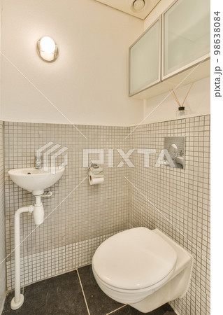 a white toilet and sink in a small bathroom with black tiles on the floor, walls and ceiling above it a white toilet and sink in a small bathroom with black tiles on the floor, walls and ceiling above it 98638084