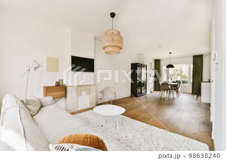 a living room with wood flooring and white walls, an area rug is placed on the floor in front of the couch a living room with wood flooring and white walls, an area rug is placed on the floor in front of the couch 98638240