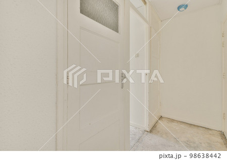 Light narrow hallway with many doors in white walls and shabby floor Light narrow hallway with many doors in white walls and shabby floor 98638442