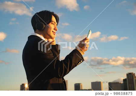 ヘッドフォンで音楽を聴く高校生　英語　リスニング　制服　ブレザー　青空　サブスク　スマホ　 98638875