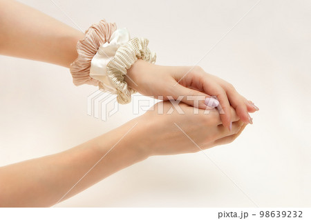 scrunchies on womans hand. Silk elastic bands on lady arm. Luxury beige and gold colors. hair tie 98639232
