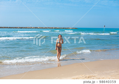 Beautiful sexy young girl in a swimsuit on the beach. Rest on the seashore 98640359