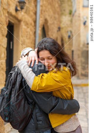 A young girl hugs a guy standing on the street 98640361