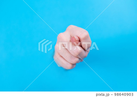Female hands sticking out through a hole on a blue background.  98640903
