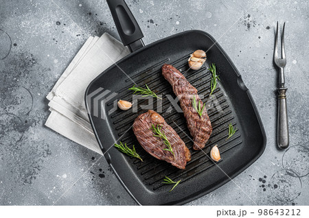 Roasted on a grill skillet Flank flap or Bavette beef meat steak with rosemary. Gray background. Top view 98643212