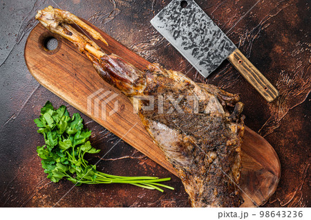 Roast lamb leg meat with herbs and spices on a cutting board. Dark background. Top view Roast lamb leg meat with herbs and spices on a cutting board. Dark background. Top view 98643236