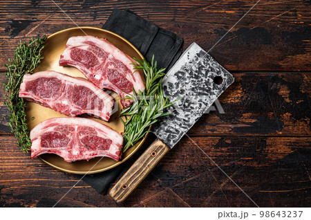 Uncooked Raw lamb loin chops steaks, saddle in plate with rosemary and thyme. Wooden background. Top view. Copy space Uncooked Raw lamb loin chops steaks, saddle in plate with rosemary and thyme. Wooden background. Top view. Copy space 98643237
