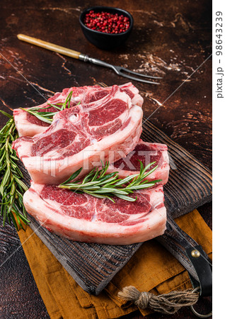 Raw fresh saddle of lamb mutton with herbs and spices on butcher board. Dark background. Top view Raw fresh saddle of lamb mutton with herbs and spices on butcher board. Dark background. Top view 98643239