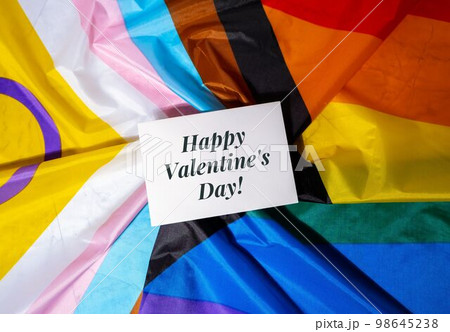 HAPPY VALENTINES DAY text Greeting card on Rainbow LGBTQIA flag made from silk material. Symbol of LGBTQ pride month. Equal rights. Peace and freedom. Support LGBTQIA community 98645238