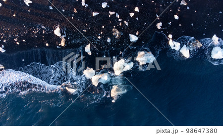 Pure Blue Glacier Ice on Black Sand Beach. Turquoise Sea Water. Icebergs at Diamond Beach in Iceland 98647380