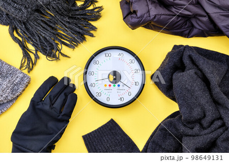 黄色背景の上の温湿度計と防寒グッズ 98649131