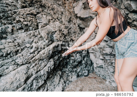 Sports Woman Climbing The Rock. Young woman With slim fit body climbing in volcanic basalt cave with beautiful sea view. The athlete girl trains in nature. Woman overcomes difficult climbing route. Sports Woman Climbing The Rock. Young woman With slim fit body climbing in volcanic basalt cave with beautiful sea view. The athlete girl trains in nature. Woman overcomes difficult climbing route. 98650792