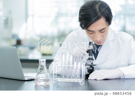 研究室で顕微鏡を除く研究者 研究室で顕微鏡を除く研究者 98653456