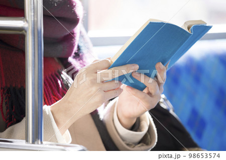 電車で座って読書をするミドル女性手元 98653574
