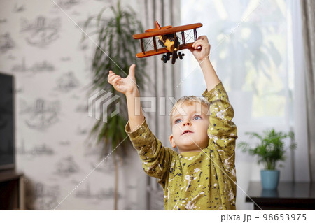 Happy child boy plays with toy airplane and dreams of becoming a pilot Happy child boy plays with toy airplane and dreams of becoming a pilot 98653975