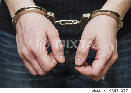 Man detained in handcuffs. Prisoner or arrested man in handcuffs 98654037