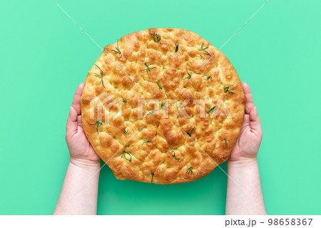 Focaccia with rosemary in woman hands, above view 98658367