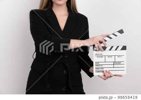 Sensuality beautiful woman with long hair, dressed in black suit in studio, holding clapperboard Sensuality beautiful woman with long hair, dressed in black suit in studio, holding clapperboard 98658419