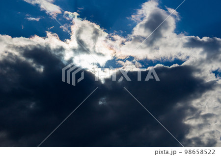 Dark clouds with a glint of sun on a blue sky background 98658522