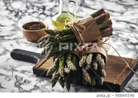 An edible, raw stems of asparagus on a marble background. An edible, raw stems of asparagus on a marble background. 98660596
