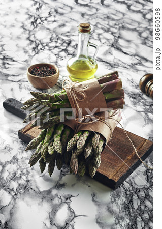 An edible, raw stems of asparagus on a marble background. An edible, raw stems of asparagus on a marble background. 98660598