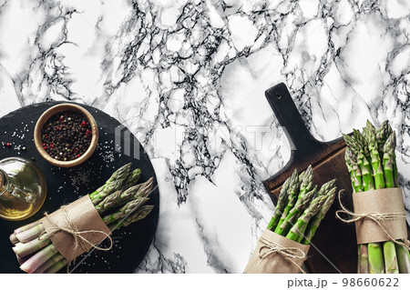 An edible, raw stems of asparagus on a marble background. 98660622