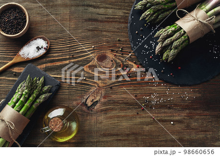 An edible, raw stems of asparagus on a wooden background. 98660656