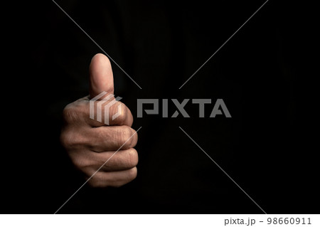 The symbol is "super ok". Young man's hand on a black background isolated close-up thumbs up to show approval and a positive sign. The symbol is "super ok". Young man's hand on a black background isolated close-up thumbs up to show approval and a positive sign. 98660911