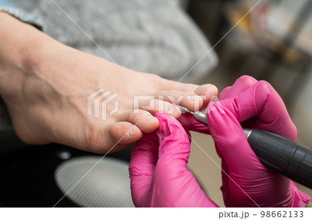 The master makes hardware pedicures to the client. Cuticle treatment.  98662133