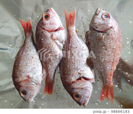 Cooking fresh fish on foil. Top view and close up. Healthy sea food. Diet meal preparation. 98666183