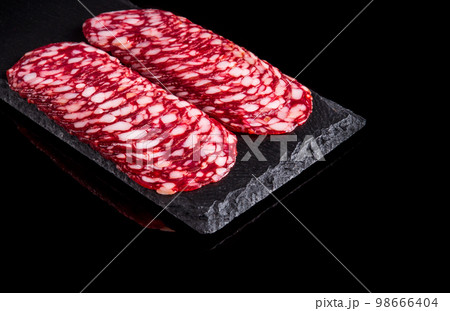 Sliced salami on a slate serving Board. Black isolated background 98666404