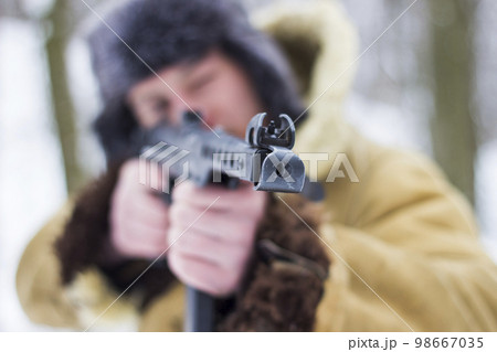 Retro photo of a soldier in the winter forest. Focus on the weapon 98667035