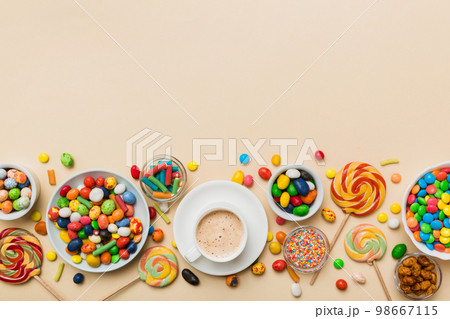 Coffee cup with chocolates and colored candy. Top view on table background with copy space 98667115