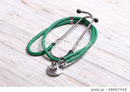 Top view of green stethoscope on white wooden background. Medical examination concept 98667448