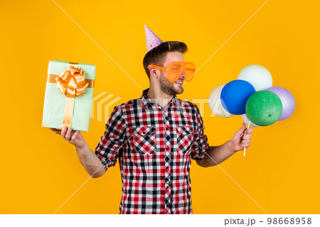Real shopaholic. guy hold festive balloons. happy holiday celebration. time for fun and presents. happy birthday or anniversary. feel cheer and joy. pure party goer. funny man in birthday cap 98668958