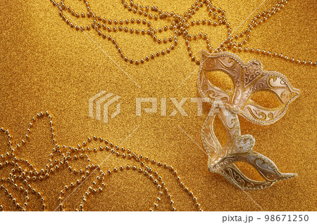 Mardi gras or carnival mask with beads on gold glowing background. Venetian mask. 98671250