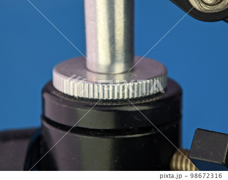 Closeup microphone mounting screw on a blue background. Closeup microphone mounting screw on a blue background. 98672316