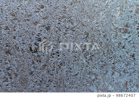 Natural background, texture of frosty patterns. Beautiful ice crystals on glass during frosts 98672407