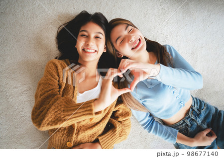 Top view two happy pretty asian women lying on carpet 98677140