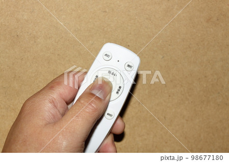 手に持った照明用のリモコン 98677180