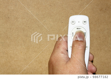 手に持った照明用のリモコン 98677182