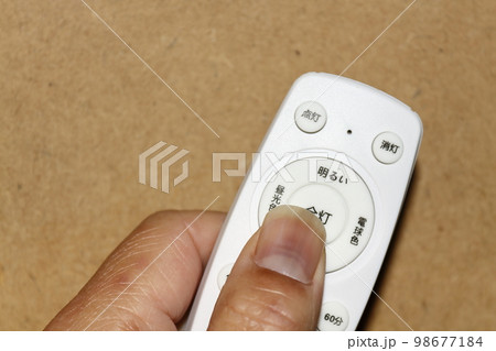 手に持った照明用のリモコン 98677184