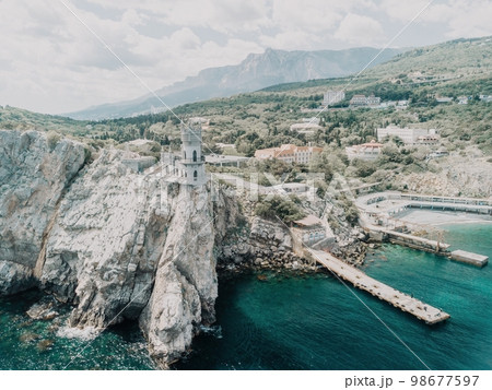 Crimea Swallow's Nest Castle on the rock over the Black Sea. It is a tourist attraction of Crimea. Amazing aerial view of the Crimea coast with the castle above abyss on sunny day. 98677597