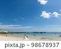 沖縄都島のビーチを歩く新郎新婦 98678937