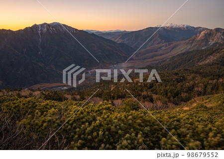 晴天の下で長野と岐阜の県境の西穂高岳稜線から見るアルプスの稜線　朝焼けする北アルプスの山々 98679552