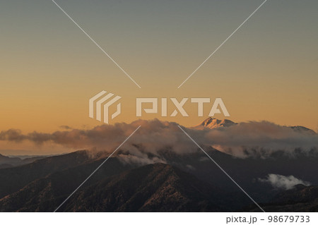 11月の早朝に晴天の下で西穂高岳の稜線で見る乗鞍岳　厳冬期の自然　朝焼けに染まるアルプスの山々 98679733