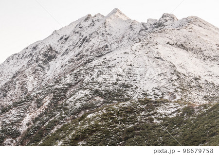 曇天の下で長野と岐阜の県境の西穂高岳稜線から見るアルプスの稜線　雲流れる北アルプスの山々 98679758