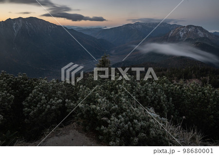 晴天の下で長野と岐阜の県境の西穂高岳稜線から見るアルプスの稜線　朝焼けする北アルプスの山々 98680001