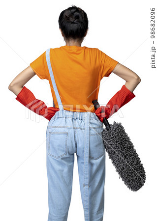 Rear view of an Asian young housewife in a protective glove holding a feather duster 98682096