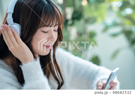 ヘッドフォンでスマホの音楽を聴く女性 98682532